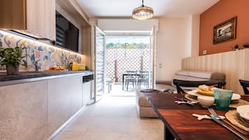 Een moderne keuken met een eethoek, een houten tafel gedekt met borden, kommen en bestek, en uitzicht op het terras.