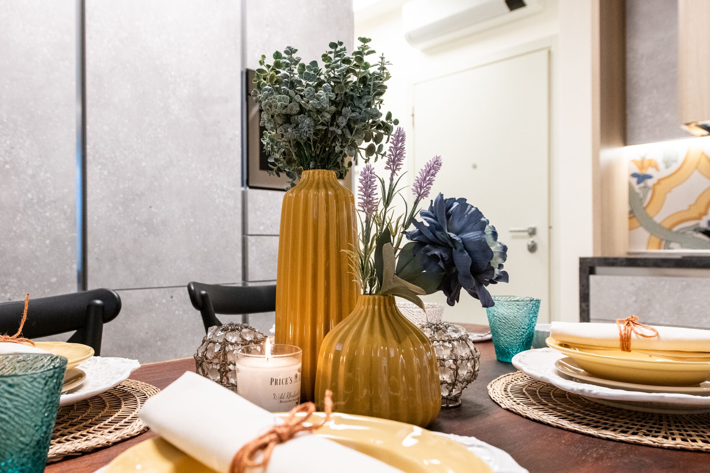 Een eettafel gedekt met borden, een kaars en decoratieve vazen.