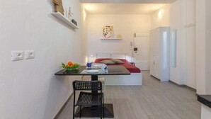 Une cuisine compacte comprenant un coin repas, un lit et un réfrigérateur.