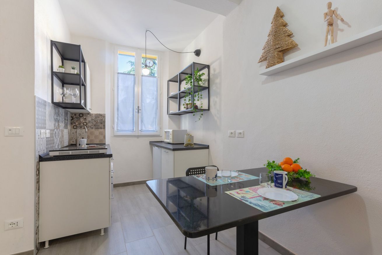 A compact kitchen with a dining table, shelves, and a window.