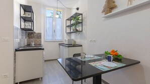 Une cuisine compacte comprenant une table à manger, des étagères et une fenêtre.