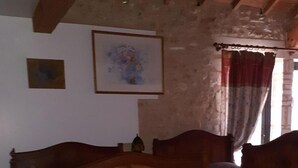 Ein Zimmer mit einem hölzernen Bett, einem Esstisch und einem Fenster mit Vorhängen.