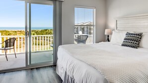 Ein Schlafzimmer mit einem großen Bett, Meerblick und einem Balkon mit einem Sessel.
