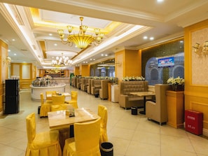 A hotel lobby with a reception desk, seating area, and a large chandelier. - Vienna International Hotel (Ye County)
