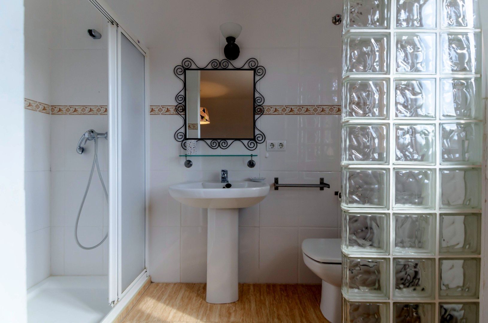 Ein Badezimmer mit weißem Waschbecken, einem Spiegel, einer Toilette und einer Dusche.