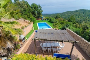Piscina en la azotea con vistas a las colinas circundantes, un patio cubierto con sillas y una pequeña estructura de juegos.