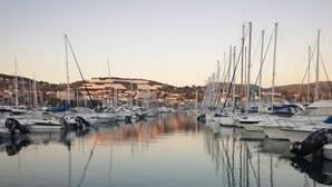 Ein Yachthafen mit mehreren Booten, die in ruhigem Wasser vor Anker liegen, umgeben von einer hügeligen Landschaft.