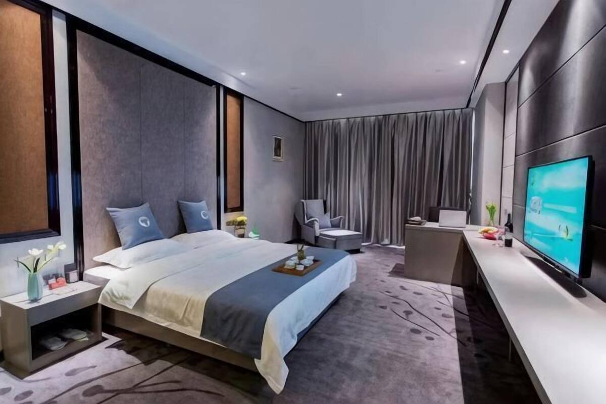 Una habitación de hotel moderna con una cama grande, televisión, escritorio y una silla.