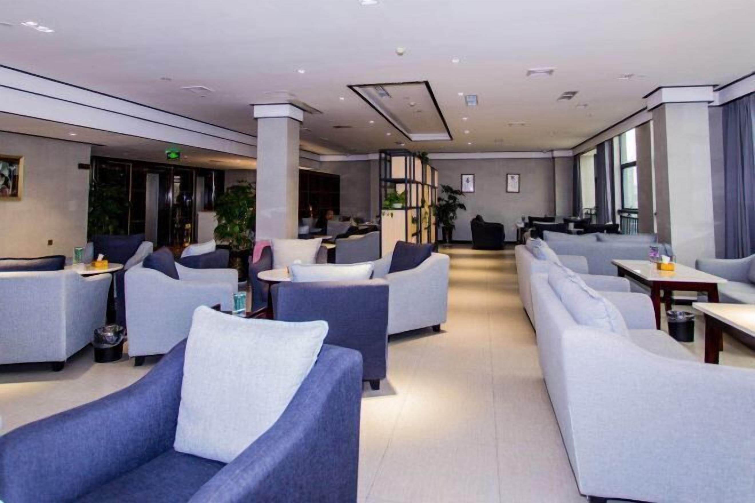 Una moderna hall d'albergo con zone relax, una reception e ampie finestre.