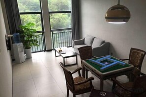 A living room with a sofa, a coffee table, and a board game. There is a potted plant and a water dispenser. - Yuting Impression Hotel (Zhongjiang)