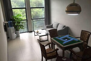 Una sala de estar con un sofá, una mesa de centro y un juego de mesa. Hay una planta en maceta y un dispensador de agua.
