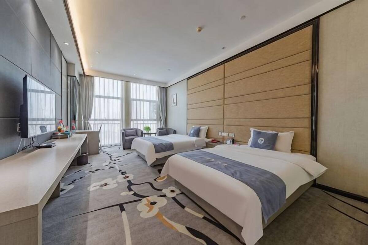 Una habitación de hotel con una cama grande, un escritorio, una silla y un televisor.