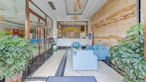 A hotel lobby with a reception desk, seating area, and potted plants. - Yuting Impression Hotel (Zhongjiang)