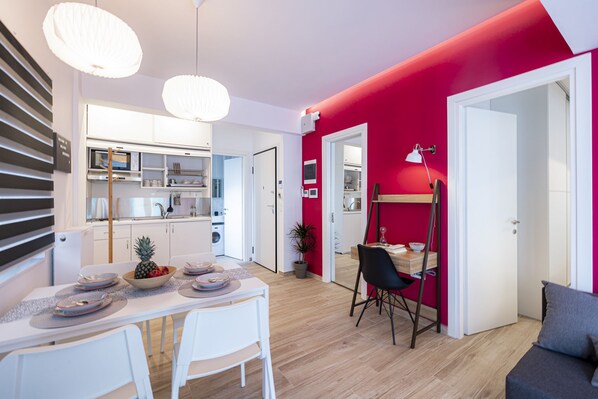 A modern apartment with a dining area, kitchen, and living space.