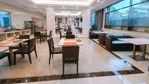 A spacious restaurant with high ceilings, a chandelier, and large windows offering views of the outdoors. - Vienna Hotel (Longmen)