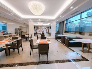 A spacious restaurant with high ceilings, a chandelier, and large windows offering views of the outdoors. - Vienna Hotel (Longmen)