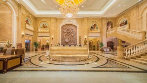 A grand lobby with a central reception desk, a chandelier, and a staircase. - Vienna Hotel (Longmen)