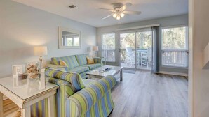A living room with a sofa, coffee table, and a ceiling fan. - PRIVATE BEACH - Gulf Peeks - Newly renovated - Bikes included - 7 Palms (Panama City Beach)