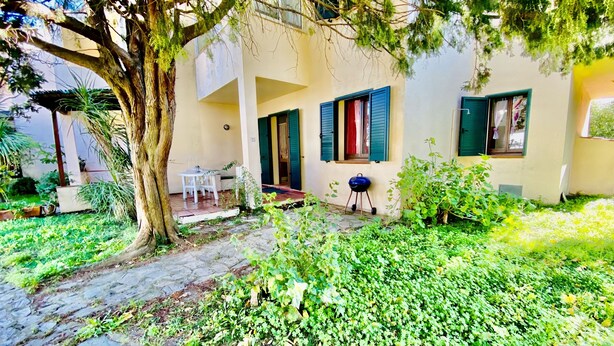A courtyard with a stone pathway, a tree, and a building with a balcony. - L'avru Di La Canna La Cinta (San Teodoro)
