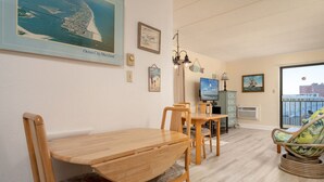Ein Essbereich mit Holztisch und -stühlen, einem Fernseher und Blick auf die Stadt.