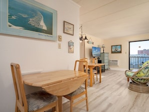 Comedor con mesa y sillas de madera, televisor y vista a la ciudad.