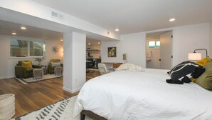 A modern hotel room with a large bed, a sitting area with a sofa and armchairs, a dining area, and a kitchen. - Bright and Modern Basement Apartment ✿ DT Neighborhood (Vancouver)