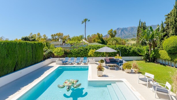 Ein Swimmingpool mit Meeresschildkröte, umgeben von Liegestühlen und Blick auf Berge.