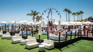Ein Hotel am Strand mit Außenbereichen, einem Riesenrad und Palmen.