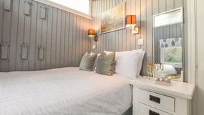 Een slaapkamer met een groot bed, een nachtkastje met een spiegel en wandlampen.