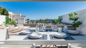 A rooftop dining area with a table set for four, overlooking a scenic view. - NEWLY BUILT Top Modern Penthouse in Puerto Banús (Puerto Banús)