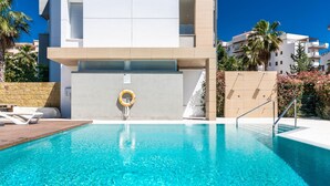 A clear blue pool with a lifebuoy, a wooden deck, and a stone wall. - NEWLY BUILT Top Modern Penthouse in Puerto Banús (Puerto Banús)