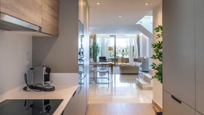 A modern kitchen with a built-in stove, a dining area with a table and chairs, and a living room with a sofa and a coffee table. - NEWLY BUILT Top Modern Penthouse in Puerto Banús (Puerto Banús)