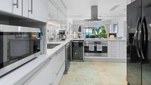 A modern kitchen with white cabinetry, stainless steel appliances, and a view of the ocean. - 1 bedroom Beachfront Condo, small pool, gorgeous sea view (Paynes Bay)