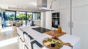A modern kitchen with a central island, built-in oven, and a dining area with a view of the outdoors.
