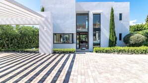 A modern two-story house with a paved driveway and a well-maintained garden.