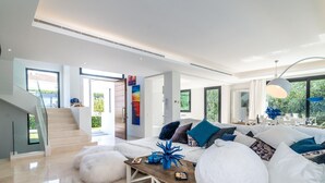 A modern living room with a large sofa, a coffee table, and a staircase leading to an outdoor area.