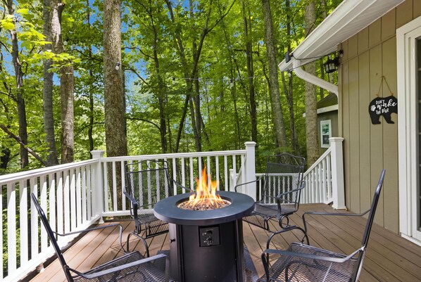 A deck with a fire pit, outdoor furniture, and a white railing.
