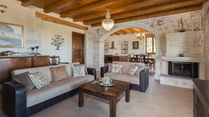 Amplia sala de estar con techo de madera, chimenea y pared de piedra.