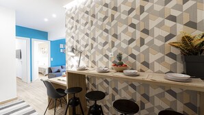 A modern kitchen with a geometric patterned backsplash, a wooden countertop, and bar stools. - Calliope (Athenian apartment close to the center) (Athens)