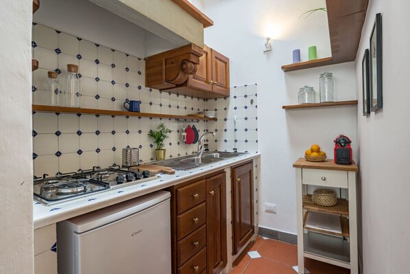 A compact kitchen with a gas stove, wooden cabinets, and a tiled backsplash. - Neri Apartment in Florence (Firenze)
