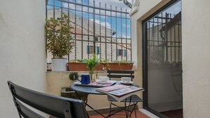 Un petit espace extérieur aménagé avec une table, des chaises et des plantes en pot.