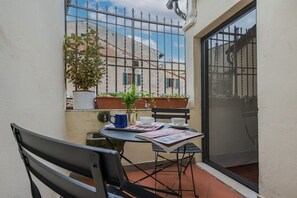 A small outdoor seating area with a table, chairs, and potted plants.