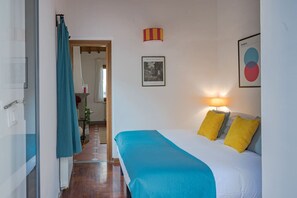 A hotel room with a bed, a nightstand, a lamp, and a framed picture on the wall.