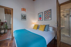 A bedroom with a bed, pillows, a wall-mounted lamp, and framed artwork. - Neri Apartment in Florence (Firenze)