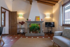 A cozy living room with a fireplace, two wall-mounted lamps, a television, and a comfortable sofa.