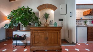 Une cuisine avec des meubles en bois, une plante en pot et un revêtement mural en carreaux.