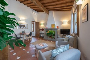 A cozy living room with a fireplace, a dining area, and a TV. - Neri Apartment in Florence (Firenze)