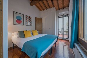 Un dormitorio con una cama, techo de madera, una puerta y vistas por una ventana.