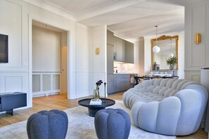 A modern living room with a round grey sofa, a coffee table, and a TV.