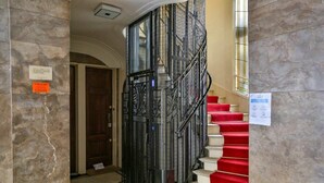 Een statige trap met rode lopers en versierde zwarte metalen balustrades.